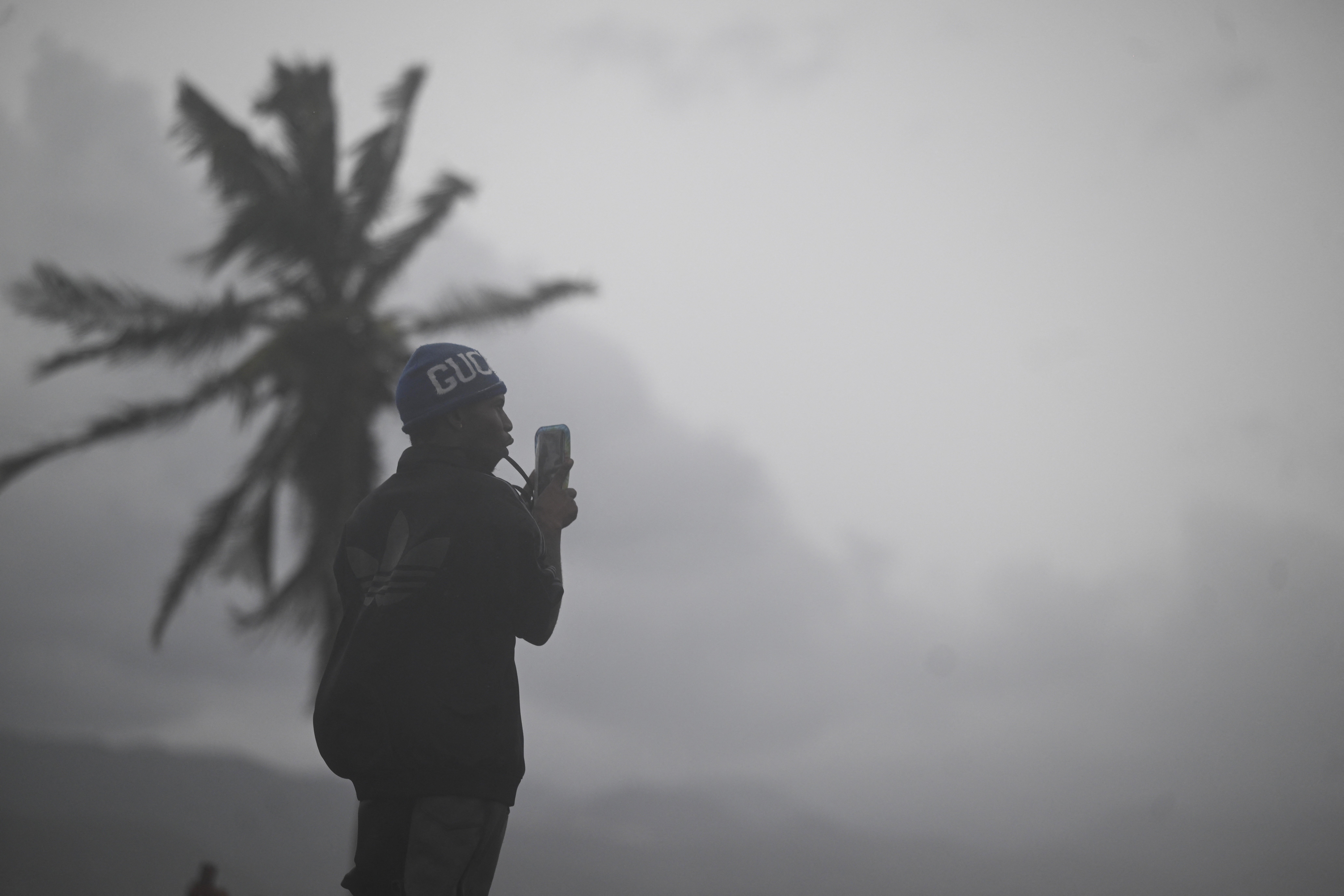 Video Shows Hurricane Melissa Descending on Jamaica With Torrential Rain and Life-Threatening Conditions as Storm Grows Stronger Than Katrina 1 A man uses his cellphone at the waterfront in Kingston on October 27, 2025. Hurricane Melissa threatened Jamaica with potentially deadly rains after rapidly intensifying into a top-level Category 5 storm, as residents scrambled for shelter from what could be the island's most violent weather on record. Melissa has already been blamed for at least four deaths in Haiti and the Dominican Republic, and was set to unleash torrential rains on parts of Jamaica in a direct hit on the Caribbean island.